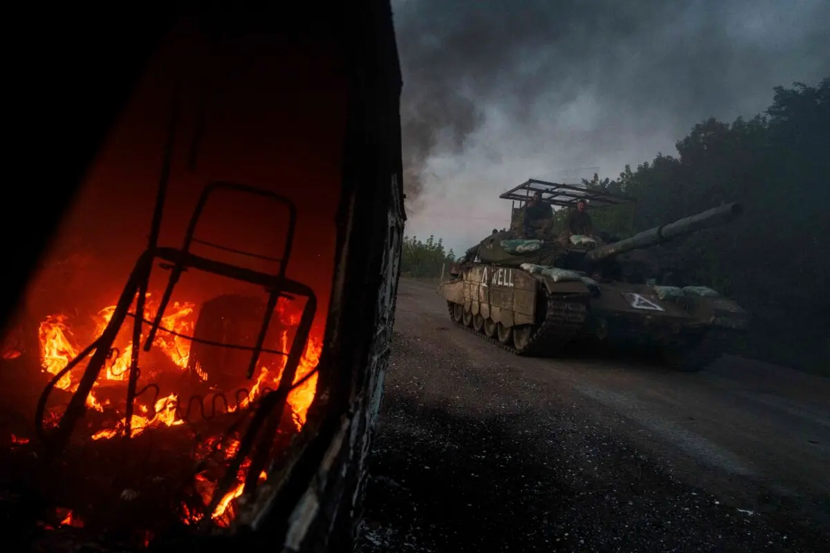 Un tanque ucraniano pasa junto a un coche en llamas cerca de la frontera ruso-ucraniana, en la región de Sumy, Ucrania, el 14 de agosto de 2024. (AP Photo/Evgeniy Maloletka)