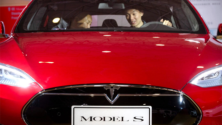 Un hombre sentado al volante de un coche eléctrico Tesla Model S expuesto en la Exposición Internacional del Automóvil de Beijing. (AP Photo/Mark Schiefelbein, Archivo)