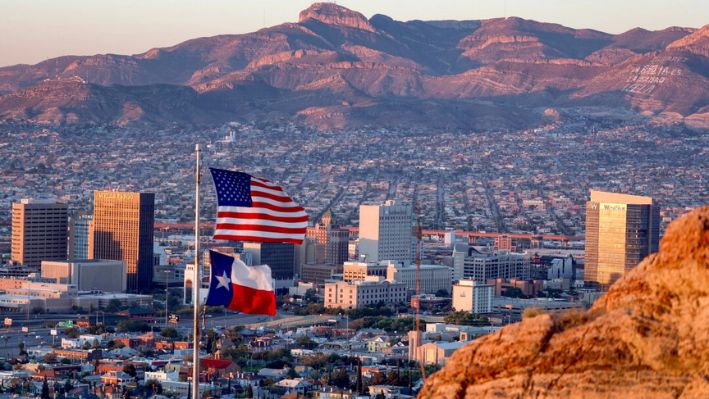 Se ven una bandera estadounidense y una de Texas ondeando frente al horizonte de El Paso y Ciudad Juárez en El Paso, Texas, el 23 de septiembre de 2022. (Joe Raedle/Getty Images)