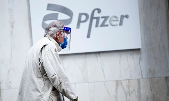 Un hombre con mascarilla y protector facial pasa por delante de la sede de Pfizer en Nueva York, el 11 de marzo de 2021. (Kena Betancur/AFP/Getty Images).