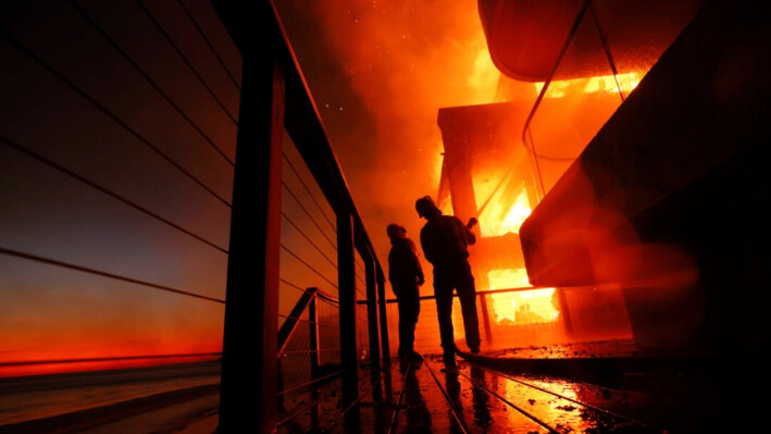 Los bomberos trabajan desde una cubierta mientras el incendio Palisades quema una propiedad frente a la playa en Malibú, California, el 8 de enero de 2025. (Etienne Laurent/AP Photo).