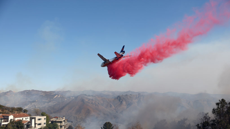 Un avión de extinción de incendios arroja el retardante de fuego Phos-Chek cerca de las casas durante el incendio de Palisades mientras los incendios forestales causan daños y pérdidas en el condado de Los Ángeles el 10 de enero de 2025 en Topanga, California. (Mario Tama/Getty Images)