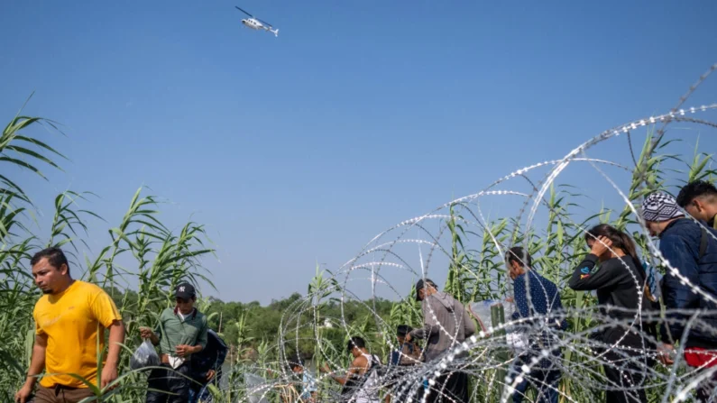 Inmigrantes ilegales de El Salvador caminan entre la maleza junto a las orillas del Río Grande después de cruzar a Estados Unidos en Eagle Pass, Texas, el 21 de mayo de 2022. Brandon Bell/Getty Images