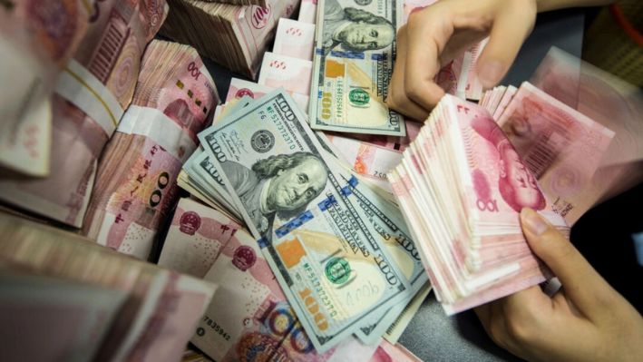 Un empleado de un banco chino cuenta billetes de 100 yuanes y de dólares estadounidenses en un mostrador bancario en Nantong, en la provincia oriental china de Jiangsu, el 28 de agosto de 2019. (AFP vía Getty Images)