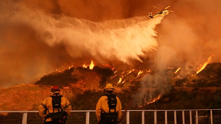 Los bomberos observan cómo se arroja agua sobre el incendio Palisades en Mandeville Canyon, en Los Ángeles, el 11 de enero de 2025. (Jae C. Hong/Foto AP)