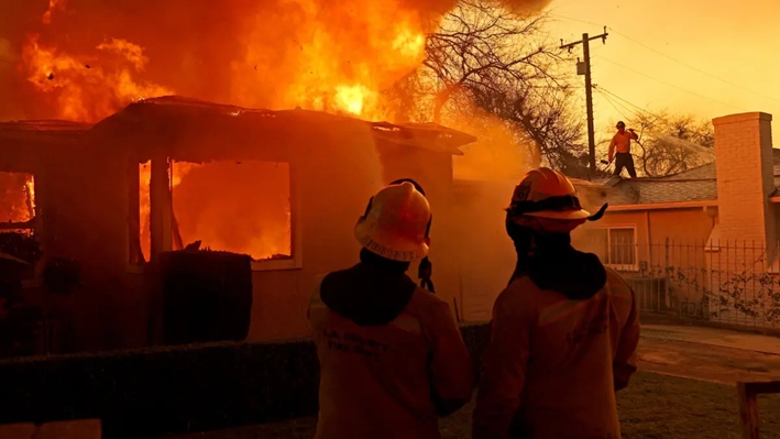 Los bomberos del condado de Los Ángeles rocían agua sobre una casa en llamas mientras el incendio Eaton avanza por la zona en Altadena, California, el 8 de enero de 2025. (Justin Sullivan/Getty Images)