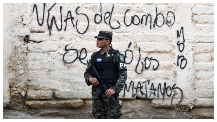 Un soldado de la Policía Militar junto a un grafiti hecho por la pandilla Mara Salvatrucha (MS-19) que dice «Niñas del Combo se van o los matamos», en el barrio El Bosque, controlado por la MS-13, en Tegucigalpa, Honduras, el 9 de mayo de 2017. (Orlando Sierra/AFP vía Getty Images)