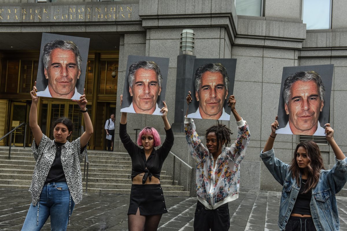 Um grupo de protesto chamado “Hot Mess” exibe cartazes de Jeffrey Epstein em frente ao tribunal federal em Nova Iorque, em 8 de julho de 2019 (Stephanie Keith / Getty Images)
