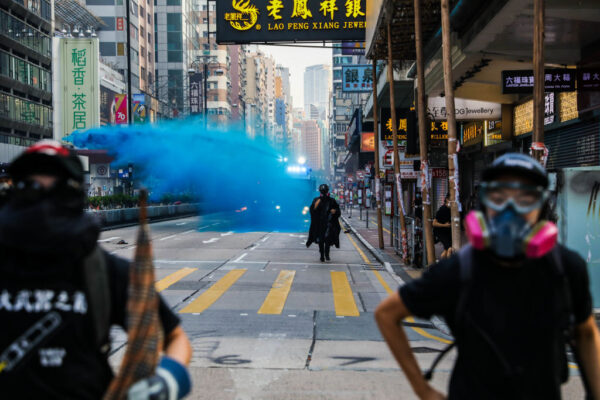 Os manifestantes fogem do avanço da polícia enquanto implantam um canhão de água em uma rodovia no distrito de Tsim Sha Tsui, em Hong Kong, em 20 de outubro de 2019 (Dale De La Rey / AFP via Getty Images)