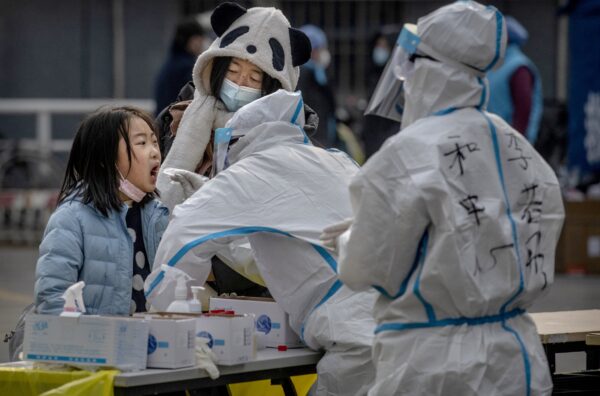 Una niña es sometida a una prueba de ácido nucleico COVID-19 por trabajadores sanitarios en el distrito de Dongcheng en Beijing, China, el 23 de enero de 2021. (Kevin Frayer/Getty Images)
