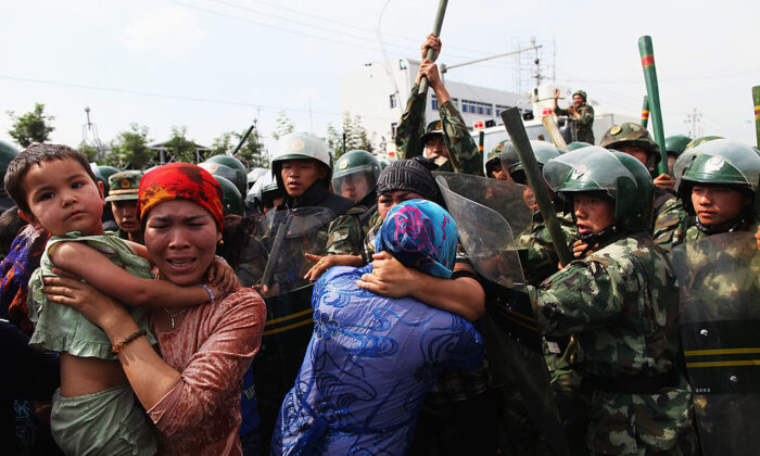 Policías chinos empujan a mujeres uigures que protestan en una calle de Urumqi, capital de Xinjiang, el 7 de julio de 2009. (Guang Niu/Getty Images)
