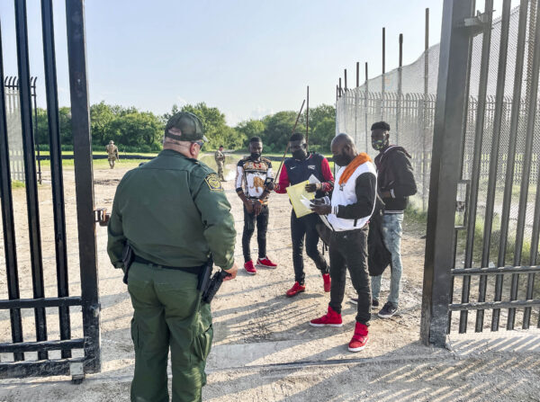 Un agente de la Patrulla Fronteriza recoge a cuatro inmigrantes ilegales de Haití que acaban de cruzar el río Grande desde México hacia Del Río, Texas, el 21 de julio de 2021. (Charlotte Cuthbertson/The Epoch Times)