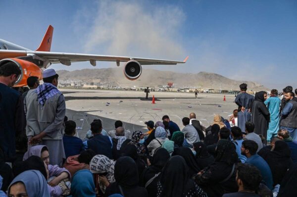 Afganos sentados mientras esperan para salir del aeropuerto de Kabul el 16 de agosto de 2021. Tras el sorprendente y rápido final de la guerra de 20 años en Afganistán, miles de personas se reunieron en el aeropuerto de la ciudad tratando de huir de los terroristas talibanes. (Wakil Kohsar/AFP vía Getty Images)