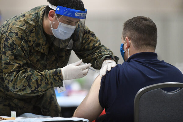 Un miembro de las Fuerzas Armadas de Estados Unidos administra una vacuna COVID-19 a un policía en un centro de vacunación comunitario de la FEMA en Filadelfia, Pensilvania, el 2 de marzo de 2021. (Mark Makela/Getty Images)