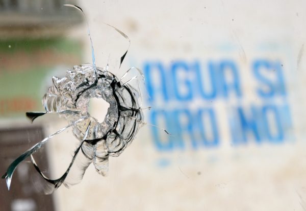 A sign reading "Water yes, Gold no!," is seen through a window with a hole of a projectile in the Andean town of Celendin, Cajamarca, Peru, on July 5, 2012, after clashes between the police and people protesting against the Conga mining project. A total of five civilians were killed and more than twenty were wounded in Cajamarca after two days of protests against the Conga mining project, while police forces deny the use of guns in their crowd control actions in the area. (STR/AFP/GettyImages)