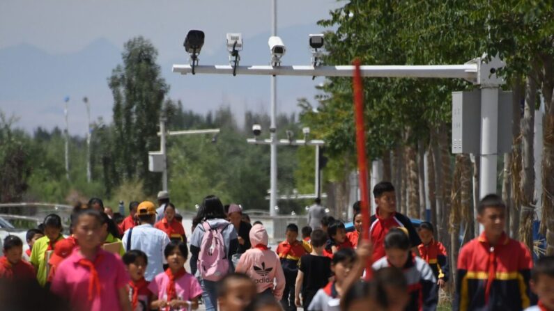 Escolares caminando por debajo de las cámaras de vigilancia en Akto, al sur de Kashgar, en la región occidental china de Xinjiang, el 4 de junio de 2019. (Greg Baker/AFP vía Getty Images)