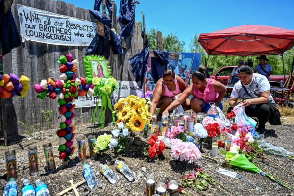 La gente coloca flores y velas en un monumento improvisado donde se descubrió un tractor-remolque con inmigrantes ilegales fallecidos en su interior, cerca de San Antonio, Texas, el 29 de junio de 2022. (Chandan Khanna/AFP vía Getty Images)
