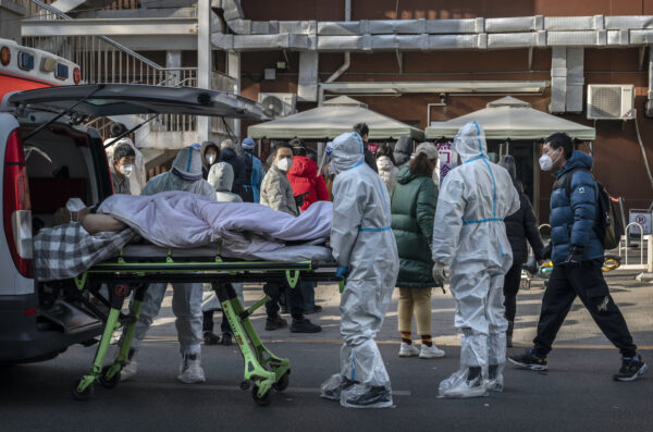 Trabajadores médicos usan EPP mientras llegan con un paciente en una camilla a una clínica de fiebre en Beijing el 9 de diciembre de 2022. (Kevin Frayer/Getty Images)
