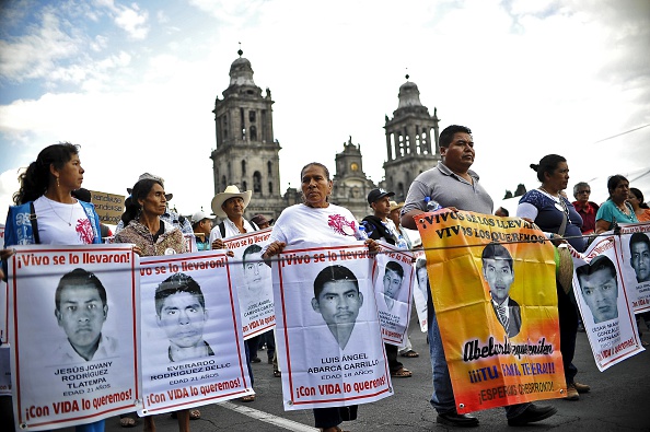 Los padres de 43 estudiantes desaparecidos supuestamente masacrados por la policía y los traficantes de drogas hace once meses tienen sus retratos durante una marcha frente a la Catedral de la Ciudad de México el 26 de agosto de 2015 (Photo credit should read YURI CORTEZ / AFP / Getty Images)