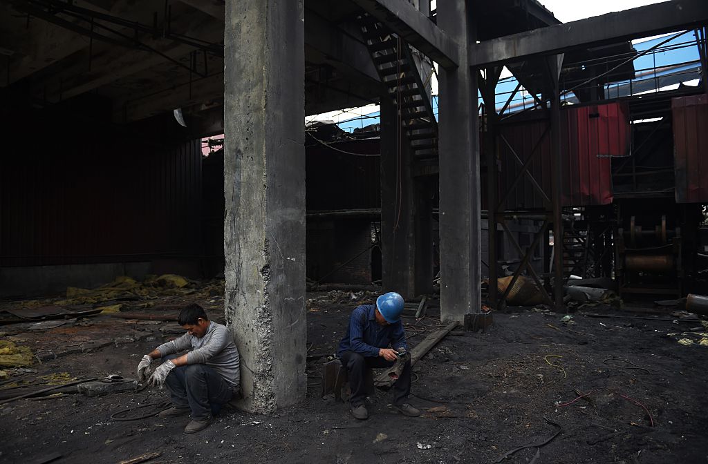 Los trabajadores de demolición toman un descanso después de la limpieza de un edificio abandonado en la Planta de Hierro y Acero Shougang Capital en Beijing el 28 de mayo de 2015. (Greg Baker / AFP / Getty Images) 