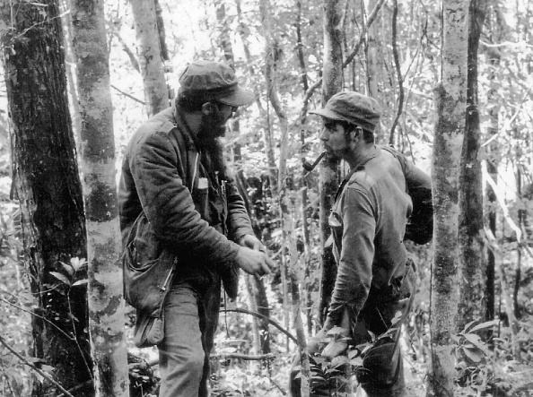 Foto del 8 de octubre de 1957 muestra al líder cubano Fidel Castro (Izq.) conversando con Ernesto 'Che' Guevara (Der.), en los bosques de la Sierra Maestra, Cuba. (ARCHIVOS / AFP / Getty Images)