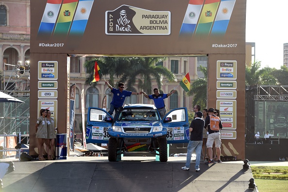 Bolivian racers of the Puch Team, Fortunato Colman and his co-pilot Victor Alarona, wave during the official launch ceremony for the 2017 Dakar Rally, on January 1, 2017 in Asuncion. The 39th Dakar Rally revs into gear on January 2, 2017 in the Paraguayan capital. From Asuncion the gruelling 9,000 km race will cross into Argentina, negotiate the Andes in Bolivia before returning to Argentina and a grandstand finish at Buenos Aires on January 14. / AFP / NORBERTO DUARTE (Photo credit should read NORBERTO DUARTE/AFP/Getty Images)