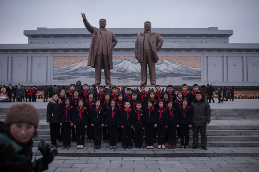 Un grupo de niños posan para una foto de grupo mientras visitan las estatuas de los últimos líderes de Corea del Norte Kim Il-Sung y Kim Jong-Il en Pyongyang el 16 de febrero de 2017. (ED JONES / AFP / Getty Images)