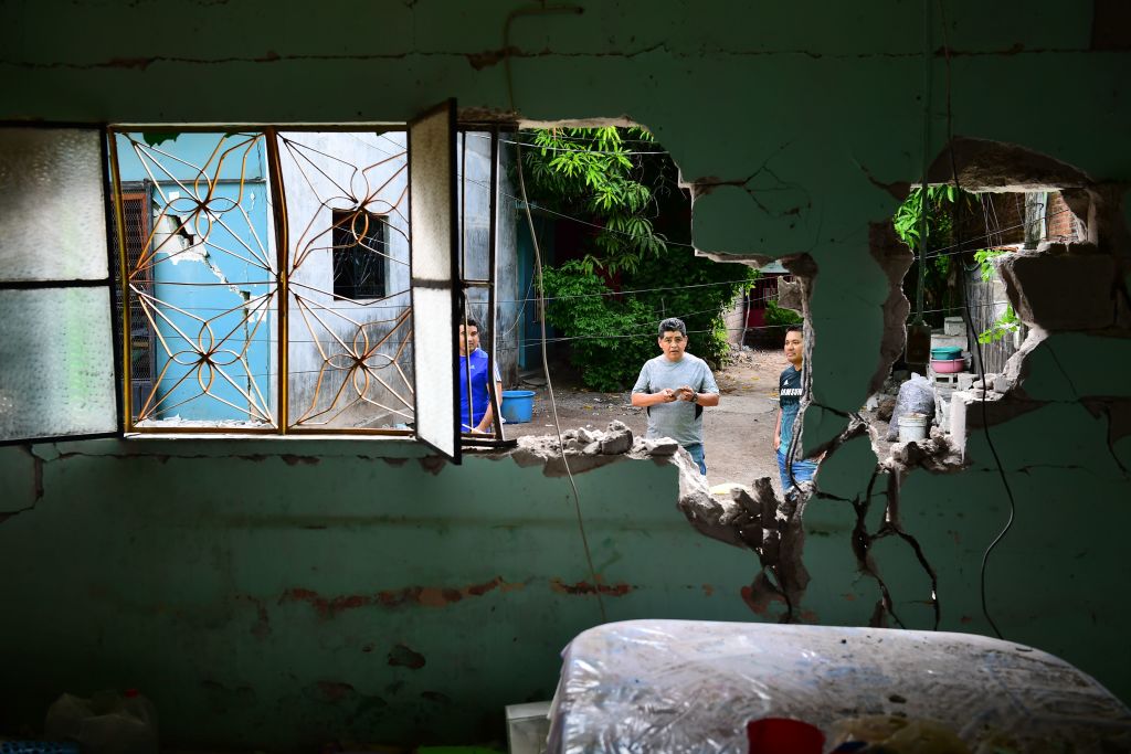 Residentes locales se encuentran fuera de su casa gravemente dañada por el terremoto de 8,2 grados de magnitud, en Juchitan, Oaxaca, México, el 10 de septiembre de 2017. (Foto debería leer RONALDO SCHEMIDT / AFP / Getty Images)